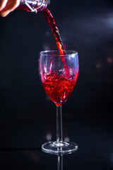 bachelor which pours red wine and spills a little by on a black background