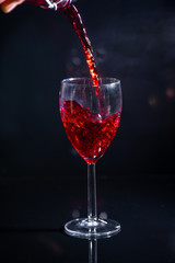 bachelor which pours red wine and spills a little by on a black background