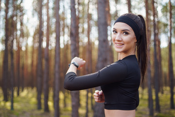 Woman running in the woods checking smartwatch. Natural light in forest. 