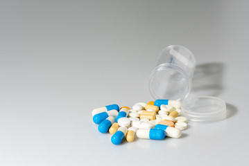 Various medicines Spilled out of plastic bottles On the white table.