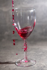 a glass of wine in which red wine is poured and spilled a little past on a cement background