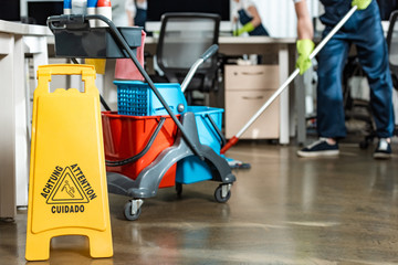 partial view of cleaner washing floor near cart with buckets