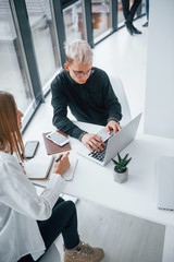 Close up view of woman and man that working and communicating together indoors in office by laptop