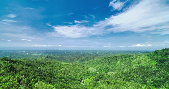 Time lapse of panoramic view of the lush green hills, tropical land and bright blue sky with white clouds, Bali, Indonesia