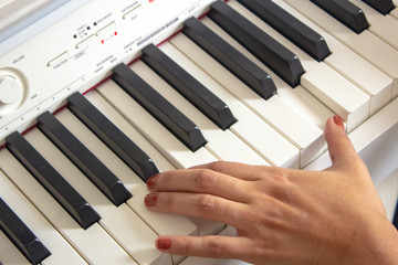 Fototapeta premium Woman practicing lessons on her white electric piano
