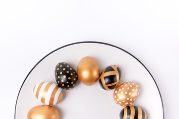 Stylish Easter golden decorated eggs on white plate isolated on white background. Trendy flat lay easter. Plate with easter eggs trendy colored. Copy space. Minimal style easter. Flat lay, top view
