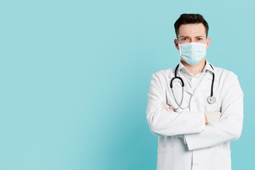 Front view of doctor with medical mask posing with crossed arms