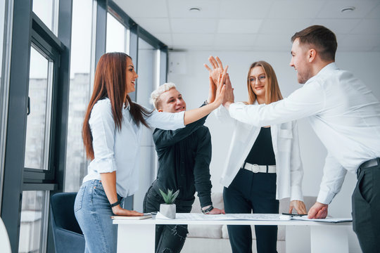 Group of young business people giving high five to each other in the office