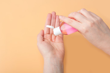 Disinfection of female hands with sanitizer gel against virus and bacteria on orange background. Coronavirus protection and healthcare concept. Safety rules during quarantine. Copy space for text