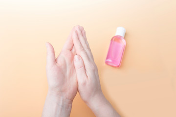 Disinfection of female hands with sanitizer gel against virus and bacteria on orange background. Coronavirus protection and healthcare concept. Safety rules during quarantine. Copy space for text