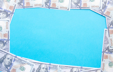 100 dollar bills around the edge of the screen. Frame of dollars on a blue background. Place for text in the middle.  Copy Space.  COVID-19