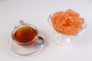 a Cup of tea and citrus marmalade in a candy bowl on a white background