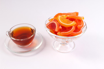 a Cup of tea and citrus marmalade in a candy bowl on a white background