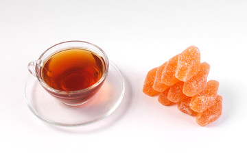a Cup of tea and citrus marmalade in a candy bowl on a white background