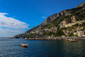 View of the town of Amalfi from the jetty with, the sea, boats and colorful houses on the slopes of the Amalfi coast in the province of Salerno, Campania, Italy.