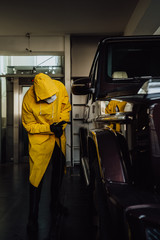 Fototapeta na wymiar Man in protective suit disinfect a car after during the new coronavirus Covid-19.