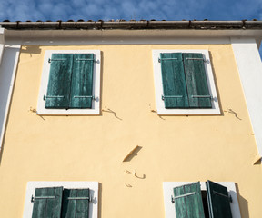 Facade of an old house with closed blue shutters on the windows