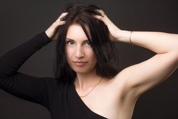 Fototapeta premium portrait of a brunette on a dark gray studio background in a black dress