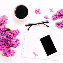 Workplace with mobile phone notebook pen glasses lilac flowers