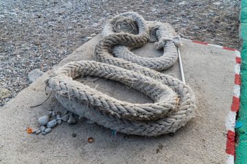 Old shabby rope lies on a concrete slab