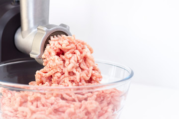 Closeup of minced meat exiting from a grinder. Healthy homemade stuffing. on a light background