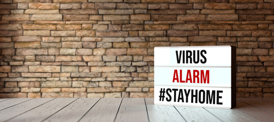 Fototapeta na wymiar lightbox with message VIRUS ALARM #STAYHOME in front of brick wall on wooden floor