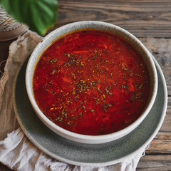 Red borscht in a gray clay bowl. Tomato soup, borsch. Wooden background. Healthy vegetarian and vegan food. Vegetable soup.