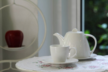 White ceramic tea set on the white wooden table.