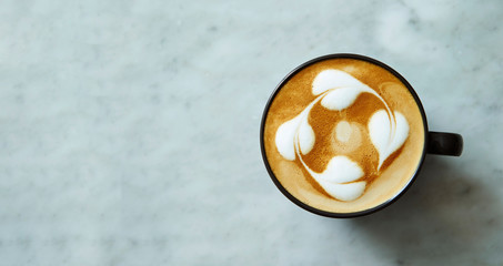 Latte in black cup on stone background 