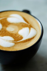 Latte in black cup on stone background 