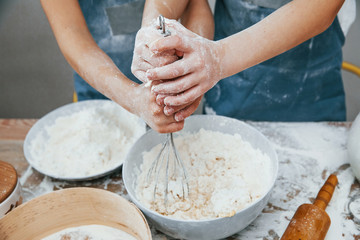Close up view of two little girls in blue chef uniform that preparing food on the kitchen