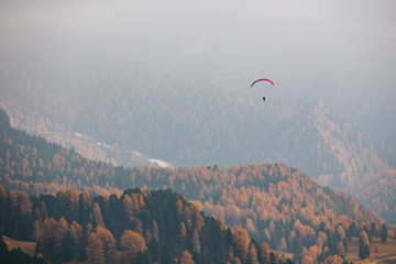 Paraglider flying over mountains in the dolomites, Italy. Sunny autumn day. - 331719192