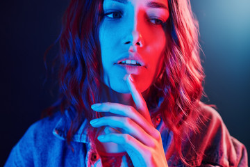 Portrait of young girl with curly hair in red and blue neon in studio