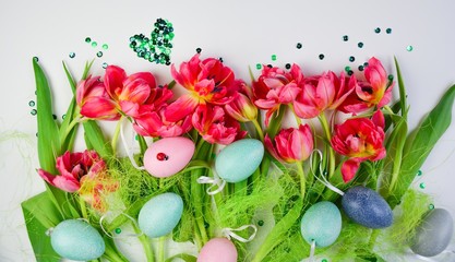 Bouquet of tulips with colorful Easter eggs on white background