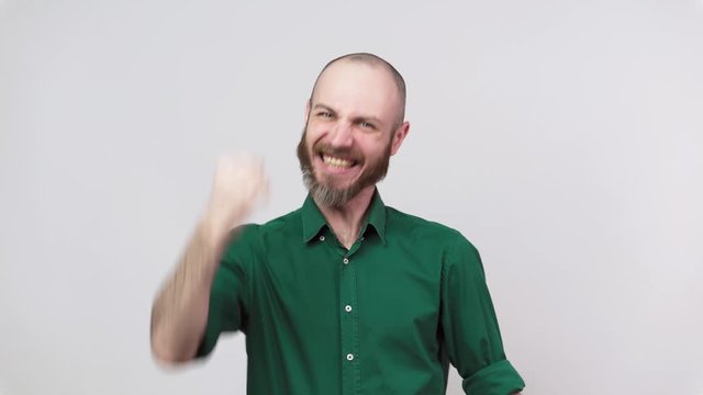 Close up of successful man celebrating a victory and raising clenched fist in the air over white background. Emotions of success, triumph, victory, winning and celebration.