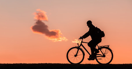 Obraz premium silhouette of a man who rides a bicycle on a sunset background