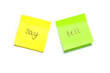Two post its on white background with say and tell