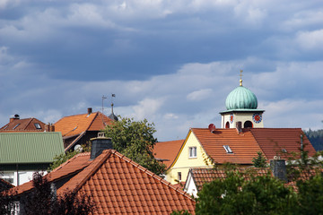 Obraz premium Zwiebelturm St. Wolfgang über Hausdächern in Stockheim Oberfranken