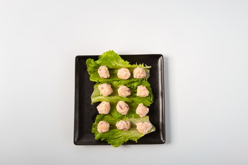 Shrimp balls made of shrimp meat and pork stuffing are placed on plates, isolated in a white background