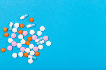 Assorted pharmaceutical medicine pills, tablets and capsules on blue background. Free space. Healthcare concept. 