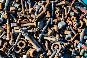 Many old rusty bolts and nuts of various sizes lie on the surface. Orange gray. Background or wallpaper.