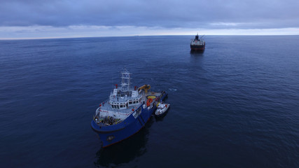 Blue tug boat with white superstructure underway, side view.