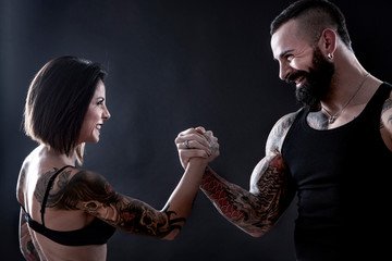 braccio di ferro tra due ragazzai  tatuati di sesso diverso che si divertono e giocano