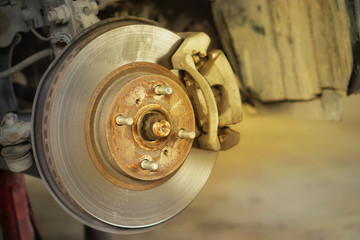 Disc brake of the vehicle for repair, in process of new tire replacement.  Car brake repairing in garage.Selective focus disc brake on car, in process of new tire replacement.Close up.