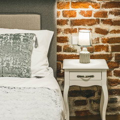 Lamp on the bedside. Pillows on the bed. Brick wall. Loft interior. Close-up.