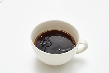 White cup of black bullet proof coffee with healthy oil on white table