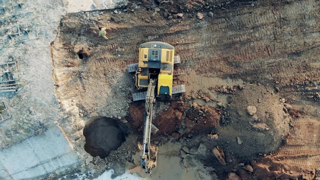 A machine digs sand while working at a big career. Construction equipment, heavy industry machinery.