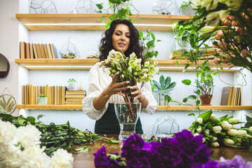 Attractive young woman florist is working in a flower shop.