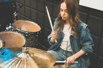 Creativity and music. Young beautiful girl plays the drums. Recording Studio. Musical equipment.