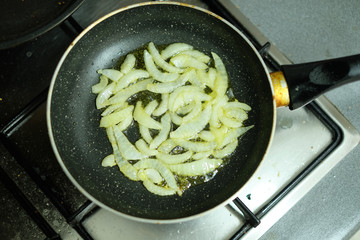 Onion slices frying in frying pan